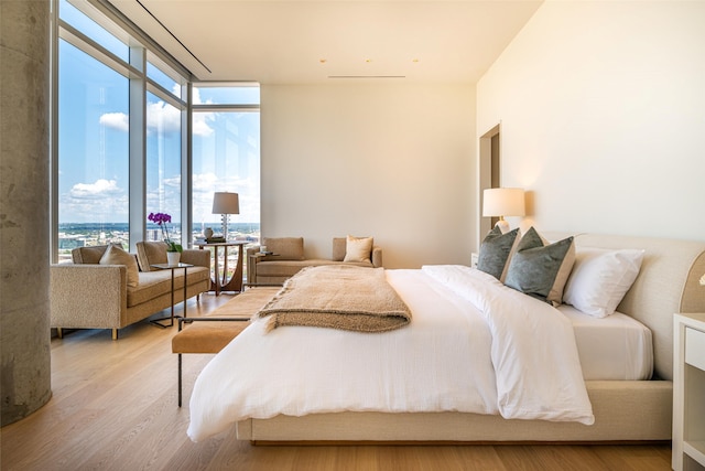 bedroom featuring light wood-type flooring and a wall of windows