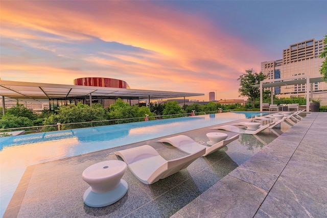 pool at dusk with a patio area