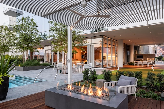 wooden terrace featuring an outdoor fire pit, a patio area, ceiling fan, and a hot tub