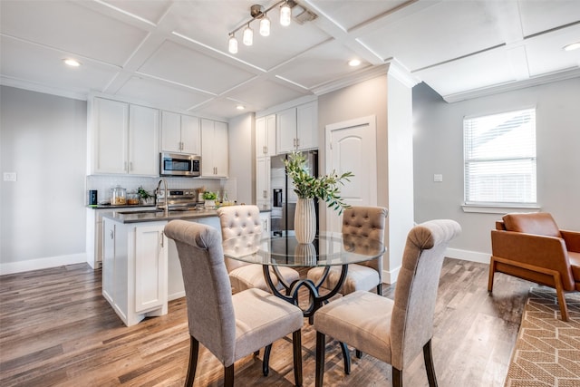 dining room featuring ornamental molding, light hardwood / wood-style flooring, and coffered ceiling