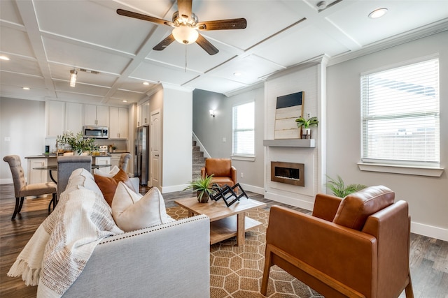 living room with coffered ceiling, crown molding, hardwood / wood-style flooring, ceiling fan, and a fireplace