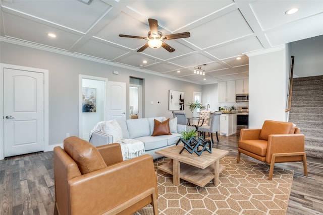 living room featuring ceiling fan, light hardwood / wood-style floors, ornamental molding, and coffered ceiling