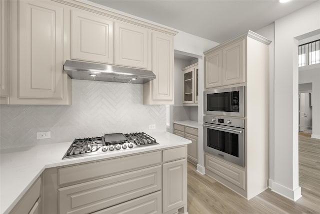 kitchen featuring appliances with stainless steel finishes, decorative backsplash, and light wood-type flooring