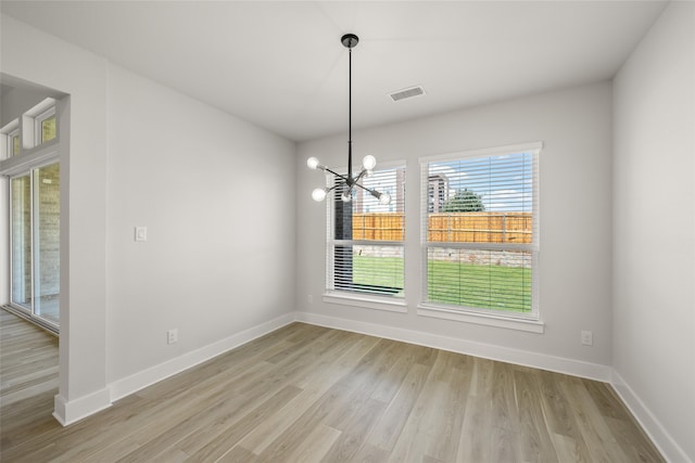 unfurnished dining area featuring light hardwood / wood-style flooring and a chandelier