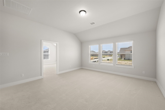 spare room featuring lofted ceiling and light colored carpet