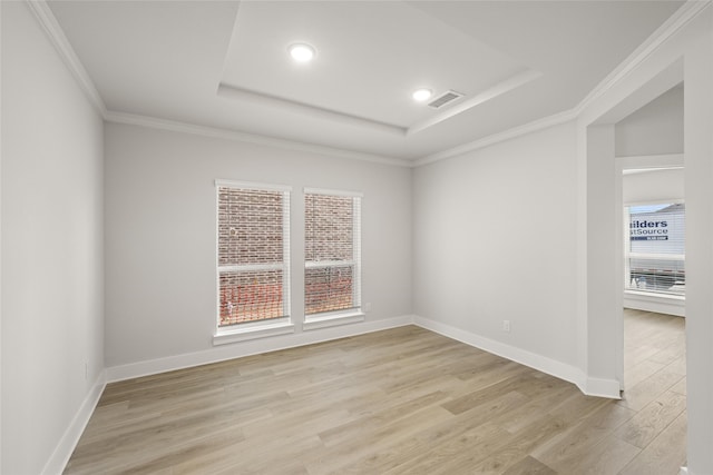 spare room featuring light hardwood / wood-style flooring, a tray ceiling, and crown molding