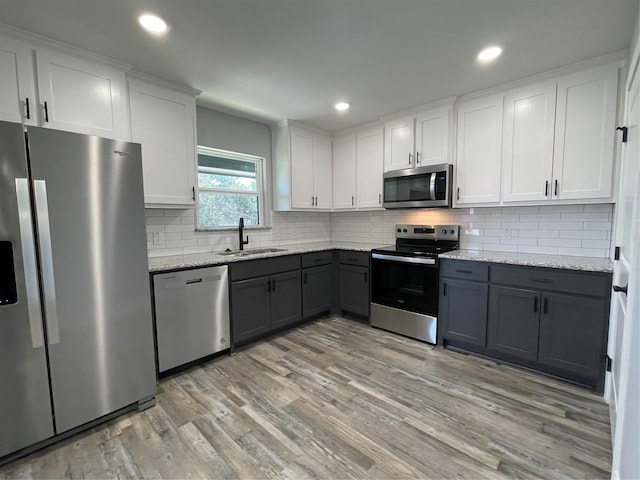 kitchen with white cabinets, decorative backsplash, stainless steel appliances, gray cabinetry, and a sink