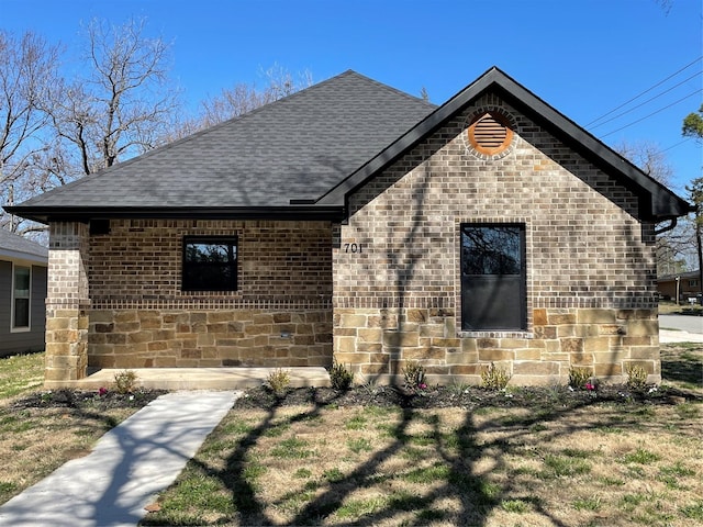 view of front facade with stone siding, a shingled roof, and brick siding