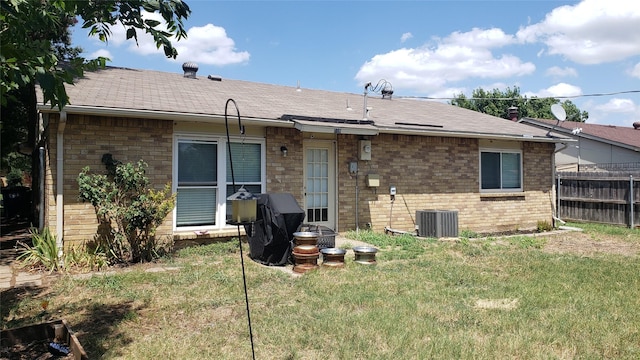 rear view of property with cooling unit and a yard