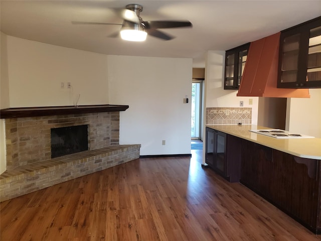 kitchen featuring white electric stovetop, ceiling fan, decorative backsplash, dark hardwood / wood-style floors, and a fireplace