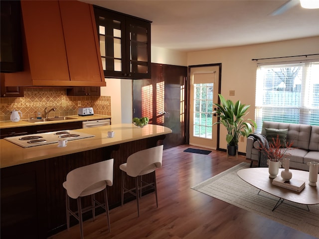 kitchen with dishwasher, decorative backsplash, sink, dark wood-type flooring, and a kitchen breakfast bar