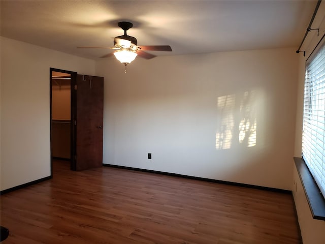 unfurnished room with ceiling fan and dark hardwood / wood-style flooring