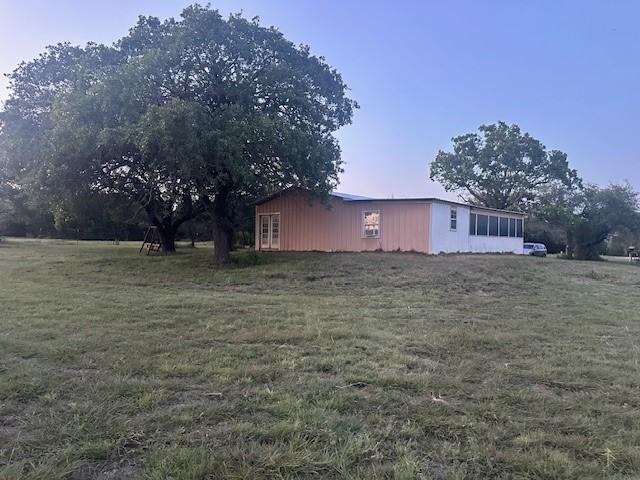 property exterior at dusk featuring a yard