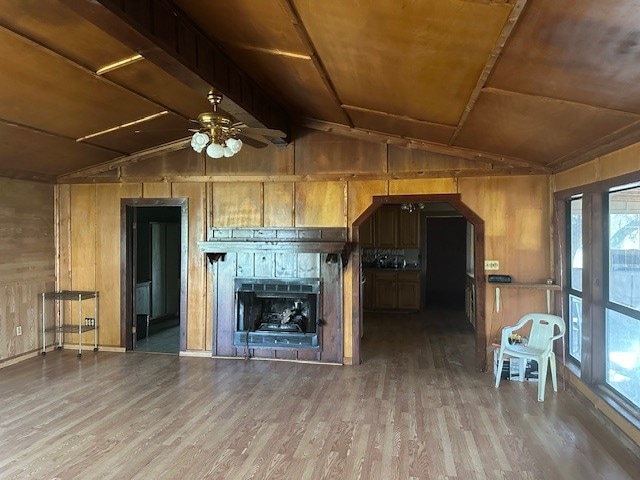 kitchen with hardwood / wood-style flooring, ceiling fan, wooden walls, vaulted ceiling, and a wealth of natural light