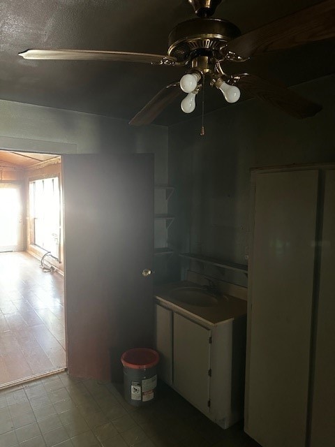 kitchen with light tile patterned flooring, white cabinetry, sink, and ceiling fan