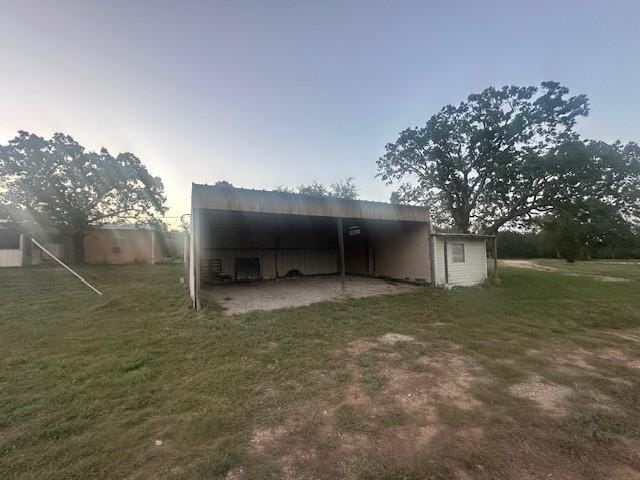 rear view of property featuring an outdoor structure and a lawn