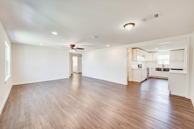 unfurnished living room with wood-type flooring, sink, and ceiling fan