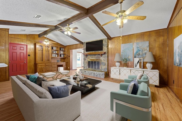 living room featuring a fireplace, a textured ceiling, lofted ceiling with beams, and wood walls