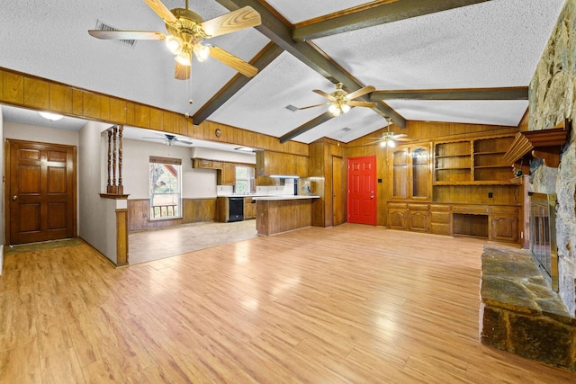 unfurnished living room featuring lofted ceiling with beams, light hardwood / wood-style floors, a textured ceiling, wooden walls, and a fireplace