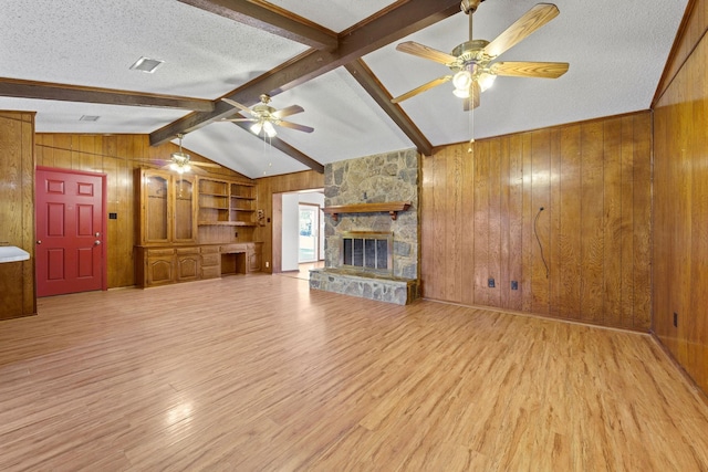 unfurnished living room with a fireplace, wood walls, and a textured ceiling