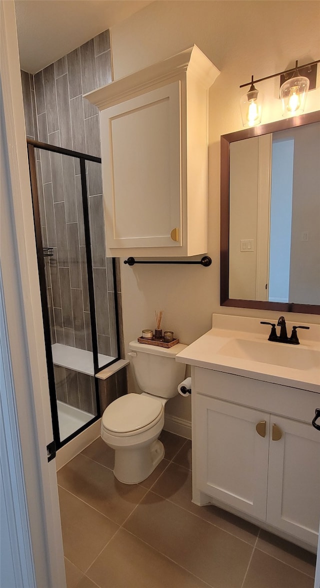 bathroom with a shower with door, tile patterned floors, toilet, and vanity