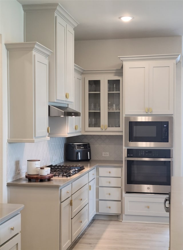 kitchen featuring white cabinetry, backsplash, light hardwood / wood-style flooring, and appliances with stainless steel finishes