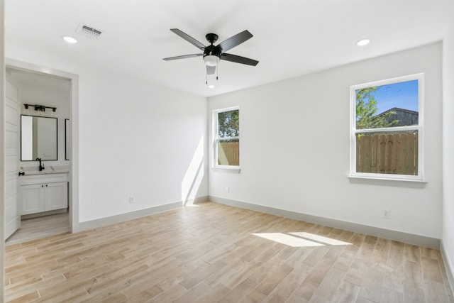 unfurnished bedroom with sink, light wood-type flooring, ceiling fan, and connected bathroom