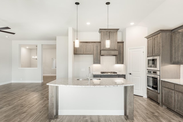 kitchen with stainless steel appliances, an island with sink, and sink