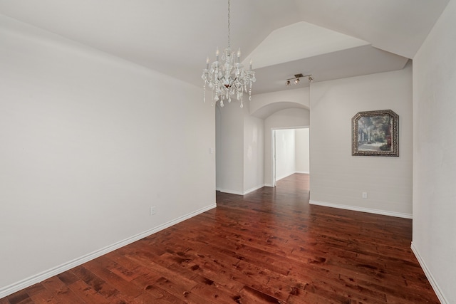 empty room featuring an inviting chandelier, wood-type flooring, and vaulted ceiling