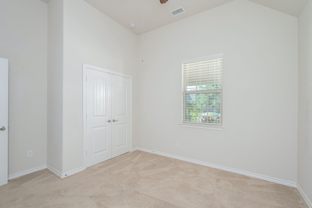 unfurnished bedroom featuring light carpet, a closet, and ceiling fan