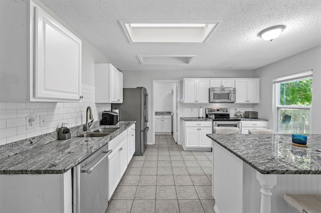 kitchen featuring dark stone countertops, a textured ceiling, white cabinets, and stainless steel appliances