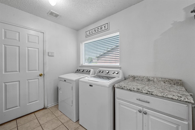 laundry area with cabinets, separate washer and dryer, light tile patterned floors, and a textured ceiling