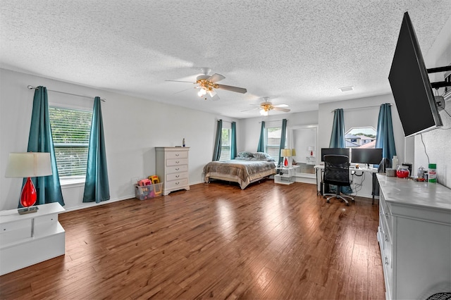 bedroom featuring dark hardwood / wood-style flooring, multiple windows, a textured ceiling, and ceiling fan