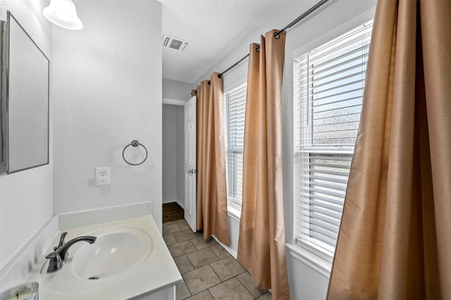 bathroom with vanity, a textured ceiling, and tile patterned flooring