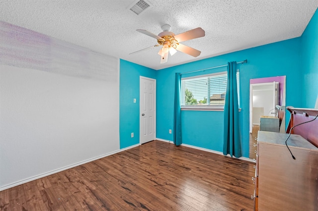 unfurnished bedroom with a textured ceiling, ceiling fan, and dark wood-type flooring