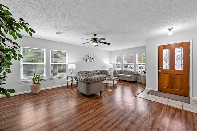 living room with a textured ceiling, ceiling fan, and hardwood / wood-style floors