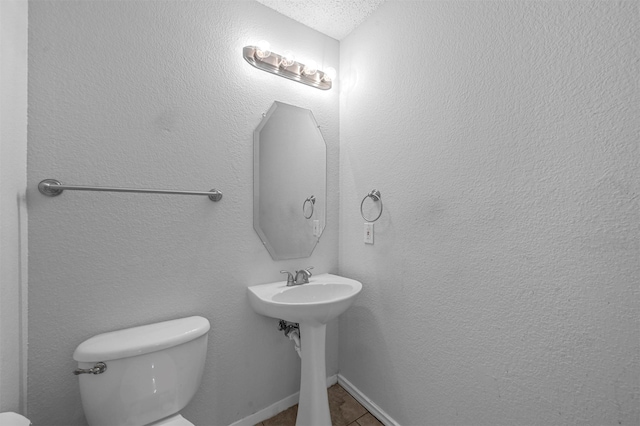 bathroom with a textured ceiling, toilet, and tile patterned flooring