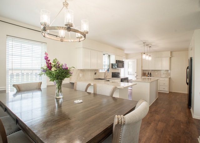 dining room with sink, dark hardwood / wood-style flooring, and a notable chandelier