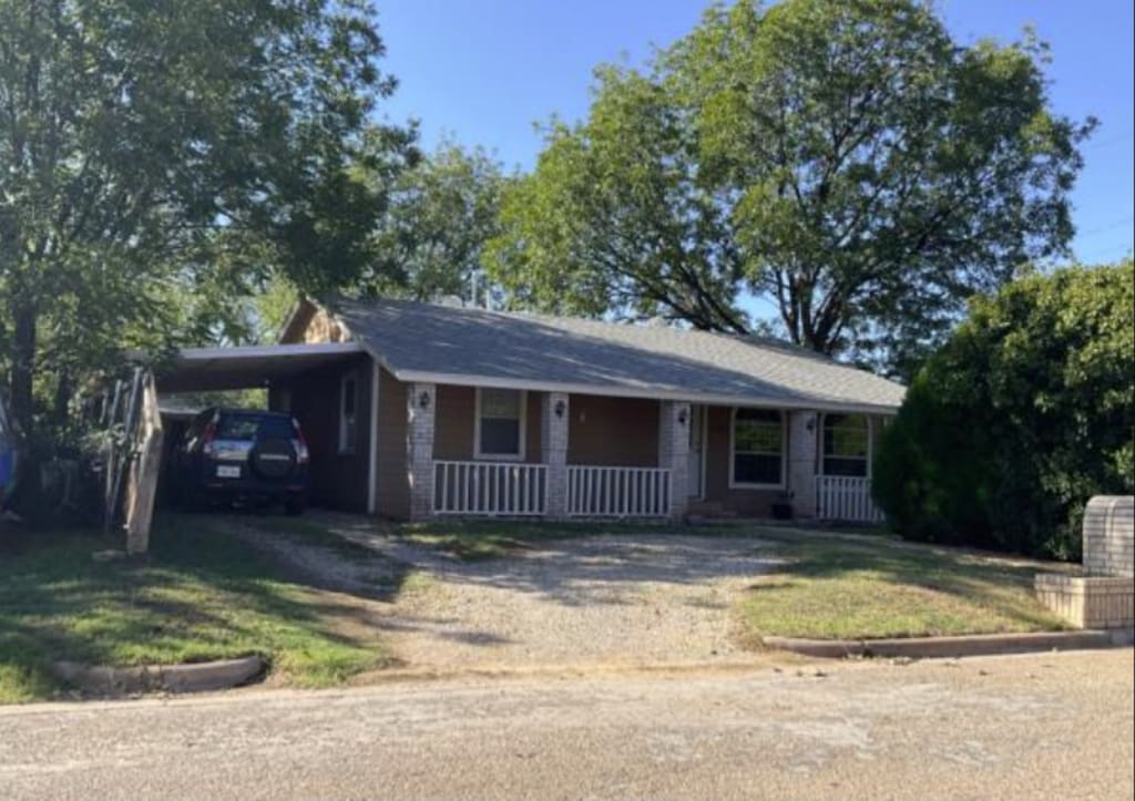 ranch-style house with a porch and a carport