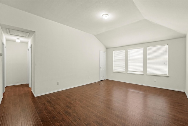 spare room featuring dark wood-type flooring and vaulted ceiling