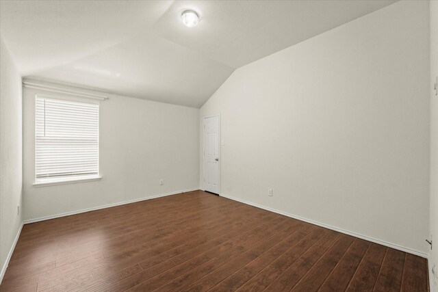 empty room featuring wood-type flooring and vaulted ceiling