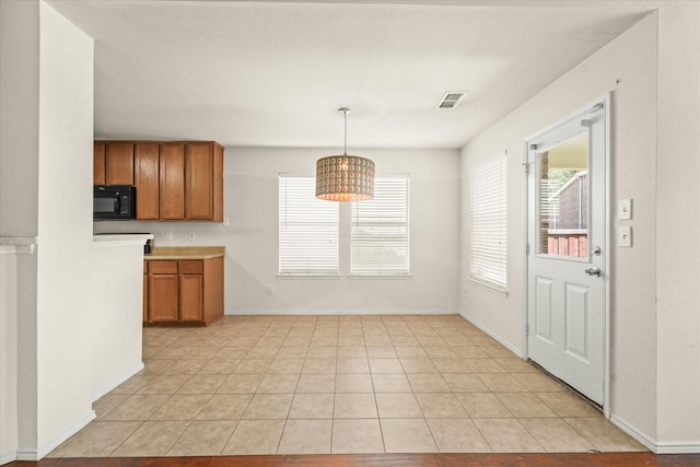 kitchen with decorative light fixtures, light tile patterned floors, and an inviting chandelier