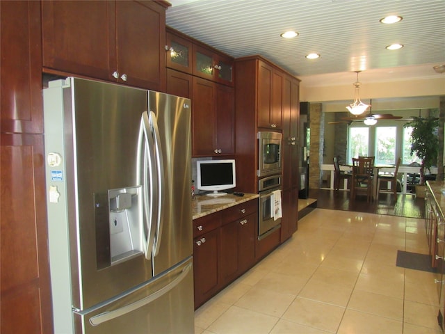 kitchen with light stone countertops, ceiling fan, hanging light fixtures, light tile patterned floors, and appliances with stainless steel finishes