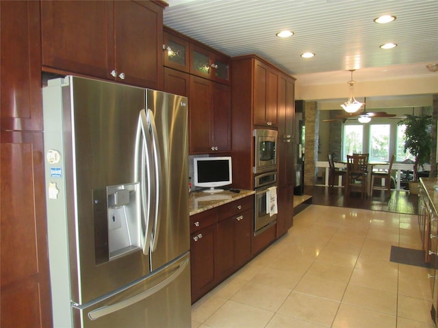 kitchen with glass insert cabinets, appliances with stainless steel finishes, light stone countertops, pendant lighting, and light tile patterned flooring