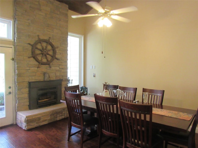 dining space with dark hardwood / wood-style flooring, ceiling fan, and a fireplace