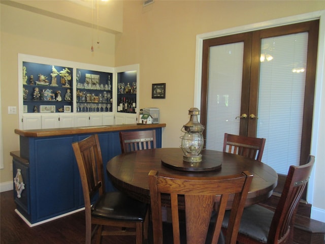 dining space featuring french doors, built in features, bar, and dark wood-type flooring