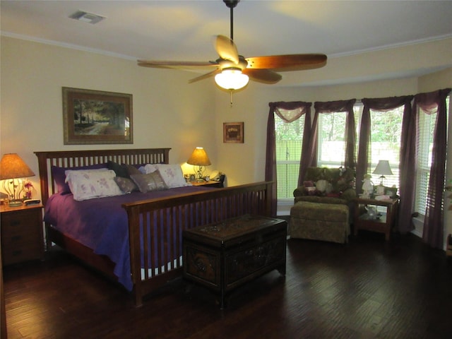 bedroom featuring visible vents, ornamental molding, dark wood finished floors, and a ceiling fan