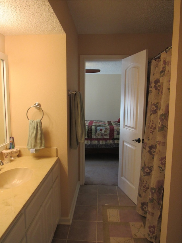 bathroom with tile patterned flooring, vanity, and a textured ceiling