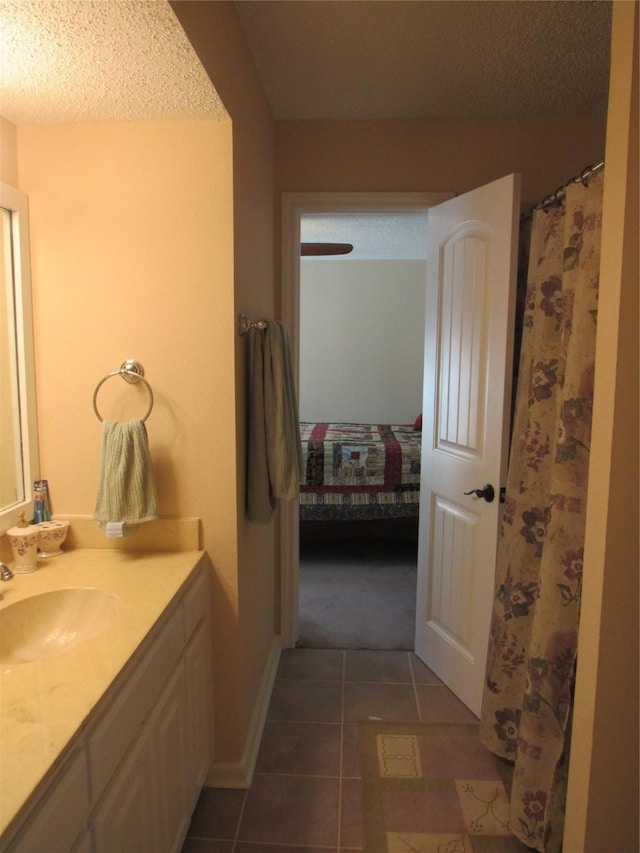 bathroom with tile patterned flooring, vanity, a textured ceiling, and ensuite bathroom