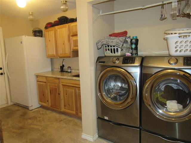 clothes washing area featuring cabinets and washer and dryer